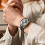 A person wearing a Breitling Navitimer Automatic 36 with an anthracite dial and grey leather strap adjusts the silver watch on their left wrist.
