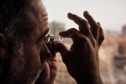 A person holds a cut stone up to a magnifying glass