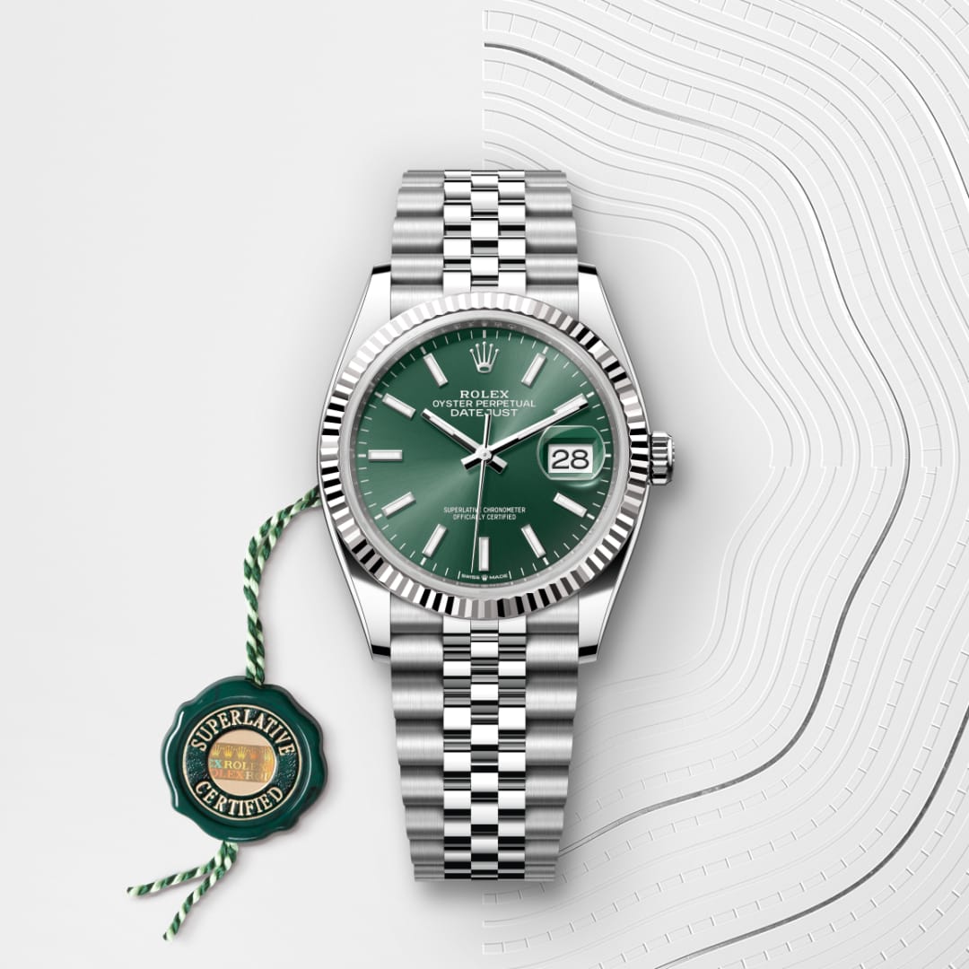 Rolex Datejust watch with a green dial and steel bracelet, next to a Superlative Certified tag on a white background.