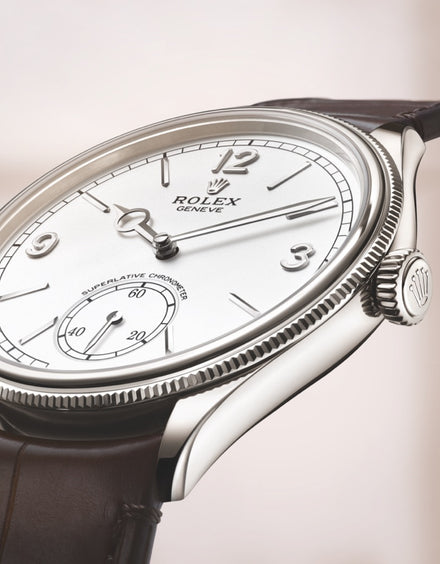 Close-up of a Rolex wristwatch with a white dial, brown leather strap, and silver case.