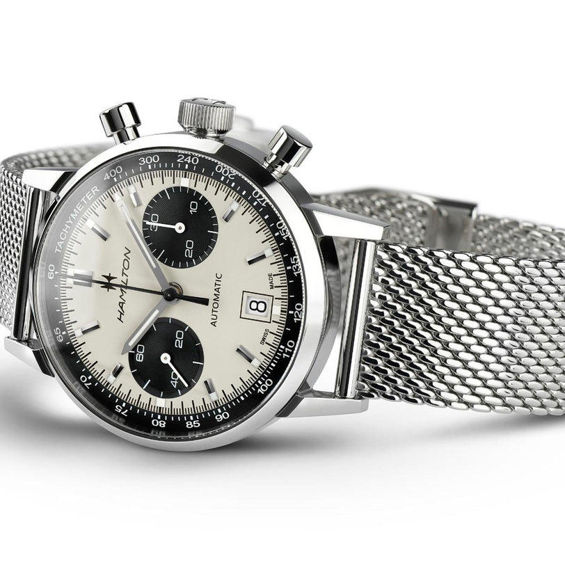 Hamilton American Classic Intra-Matic Auto Chrono wristwatch with a panda dial, two black subdials, tachymeter scale, and stainless steel mesh bracelet, elegantly displayed at an angle.