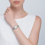 A woman in a white sleeveless top wears the Cartier Panthère de Cartier Small Model silver wristwatch, her hand resting near her collarbone.