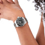 A person wearing a TAG Heuer Aquaracer Professional 300 Date with a stainless steel case and black dial holds their arm near their face against a white background.