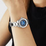 A person in a sleeveless black turtleneck wears the TAG Heuer Aquaracer Professional 200 Date, featuring a blue face, diamond markers, and a stainless steel case.