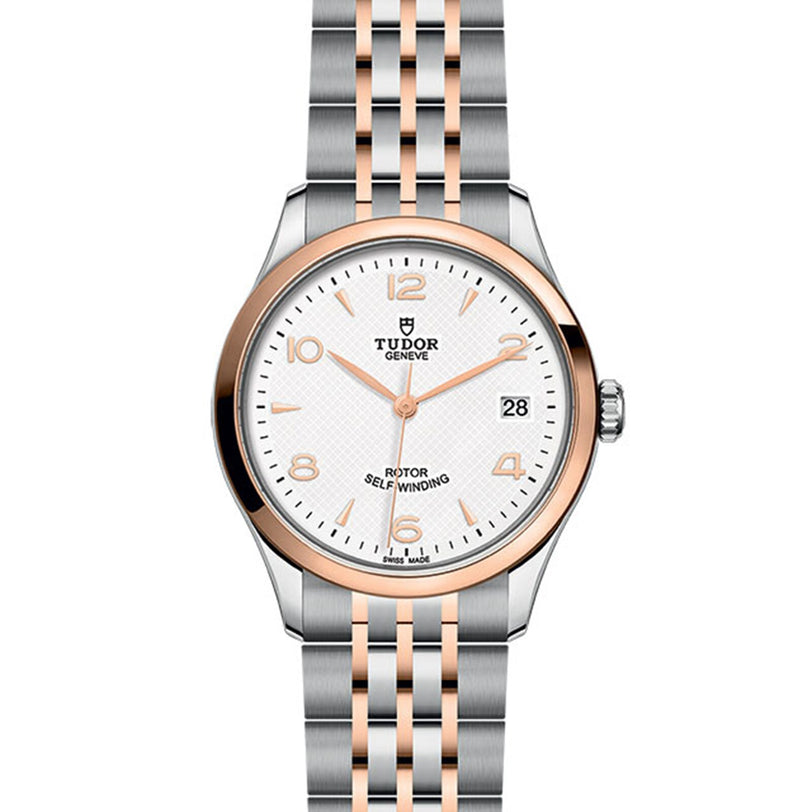 The TUDOR 1926 wristwatch features a silver and rose gold metal band, white textured dial, gold hour markers, 3 o’clock date window, and TUDOR Genève branding—crafted by the brand founded by Rolex’s creator.