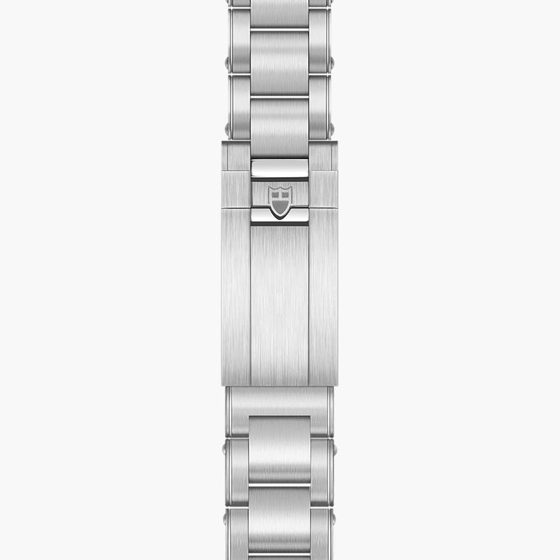 Close-up of a silver metal clasp from the TUDOR Black Bay Chrono watch, featuring an engraved shield logo at its center.
