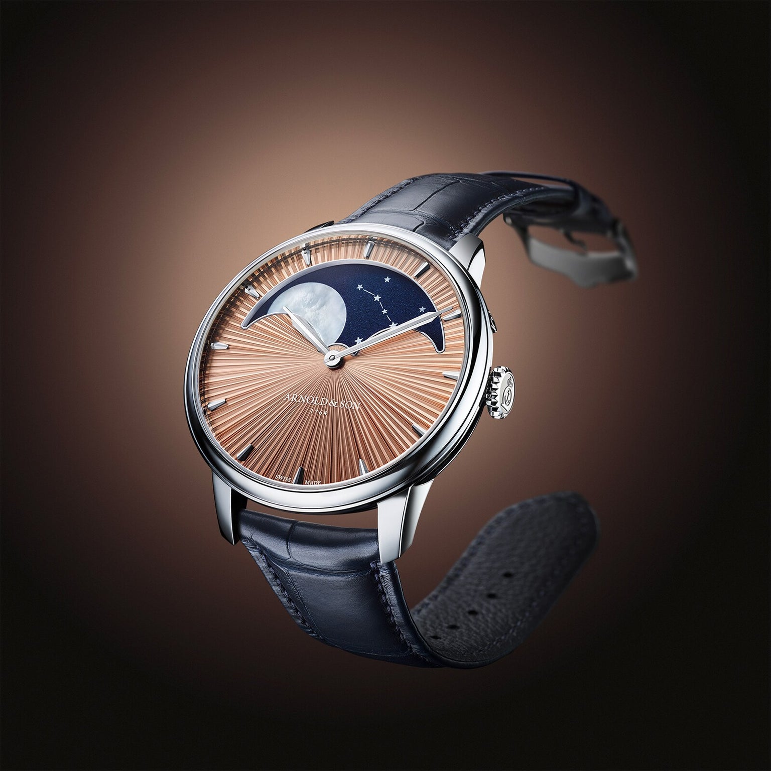 The Arnold & Son Perpetual Moon 41.5mm Platinum features a brown sunburst dial, moonphase display, and black leather strap, showcased against a brown gradient background.