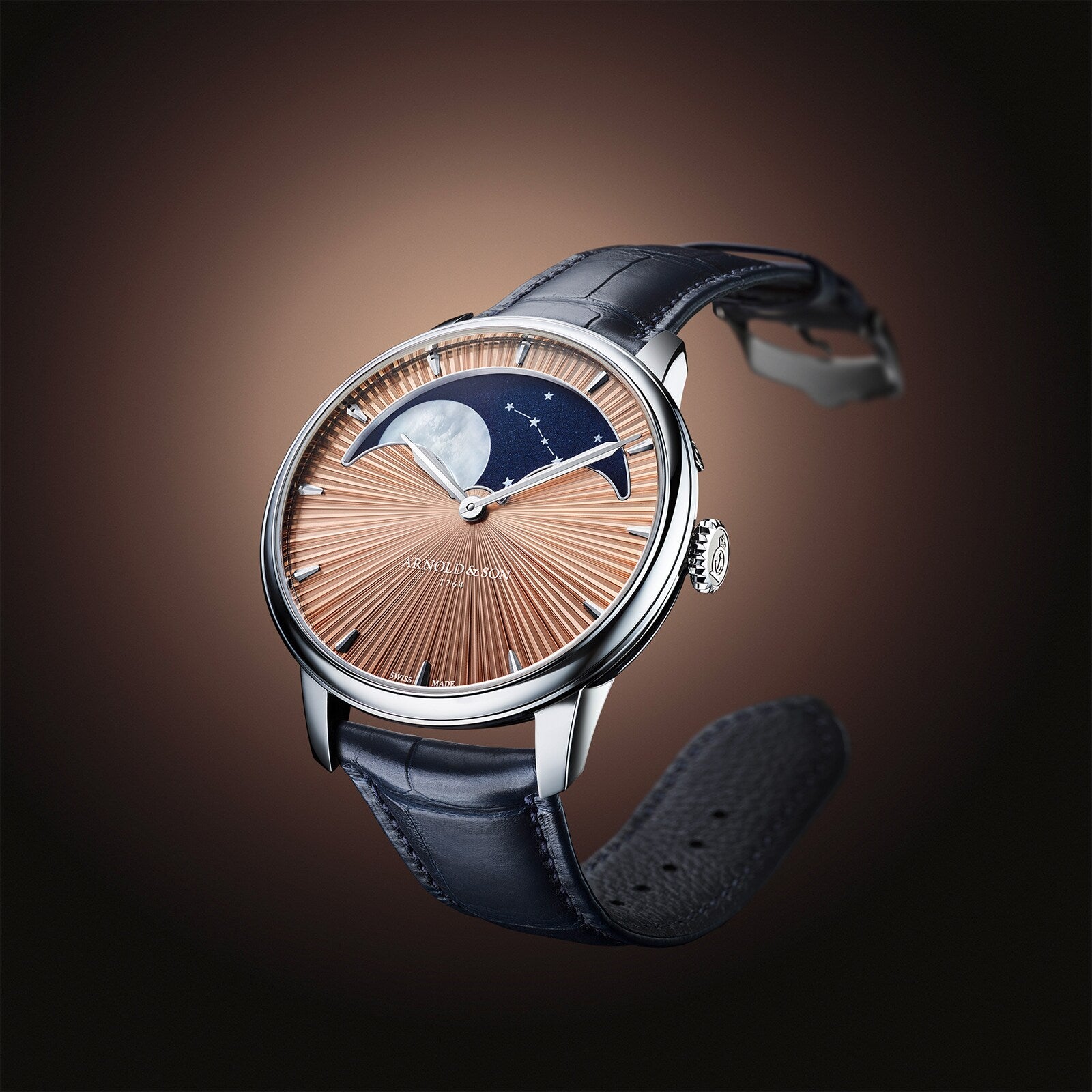 The Arnold & Son Perpetual Moon 41.5mm Platinum features a brown sunburst dial, moonphase display, and black leather strap, showcased against a brown gradient background.