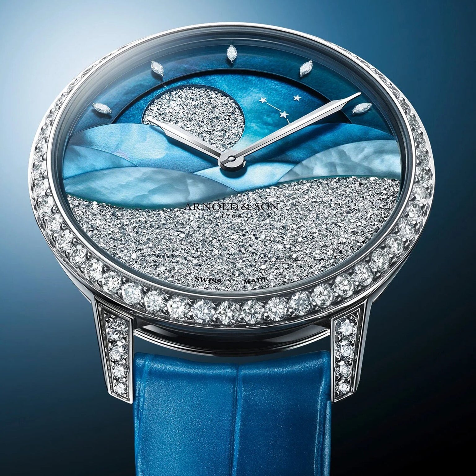The Arnold & Son Perpetual Moon 38 White Gold Mintnight features a diamond bezel, blue strap, and a dial with a starry night sky design accented with sparkling details.