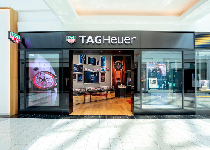 TAG Heuer store front in a mall with watch displays and large brand signage visible.