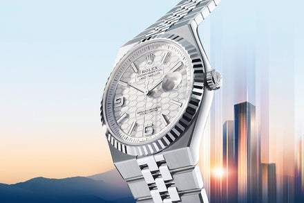 A silver Rolex watch with a patterned dial is displayed against a cityscape at sunset.